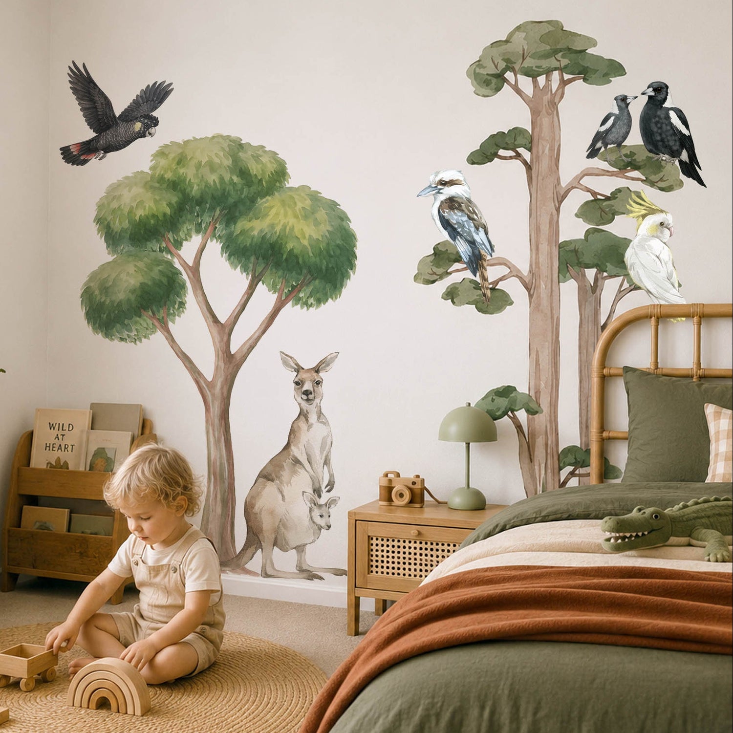 Child playing with toys in a room with tree and animal wall decals.