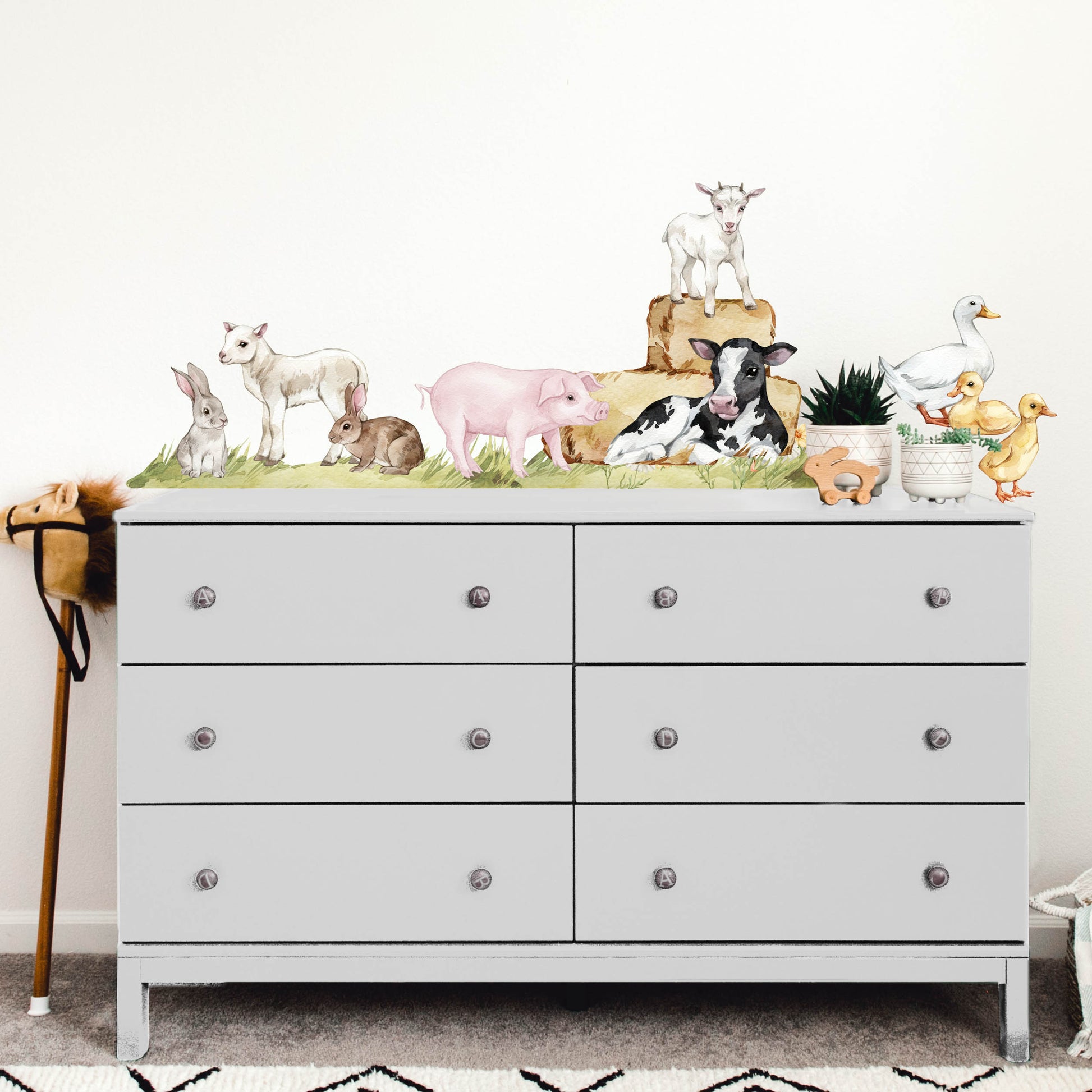 Farm animal wall decals sitting above a cupboard in a childs nursery